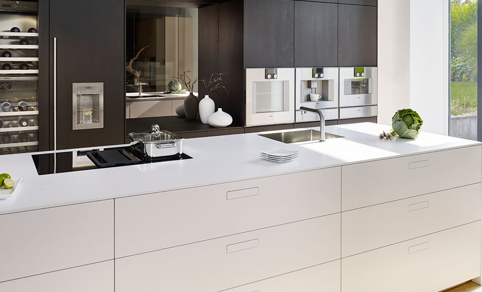 Schwarze Küchenwand mit Küchengeräten und Weißer Kücheninsel mit Arbeitsfläche 